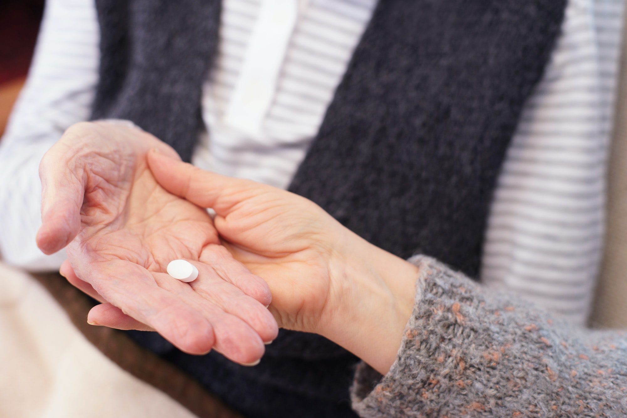 Senior being handed a daily medication from caregiver acquired through Medicare Part D